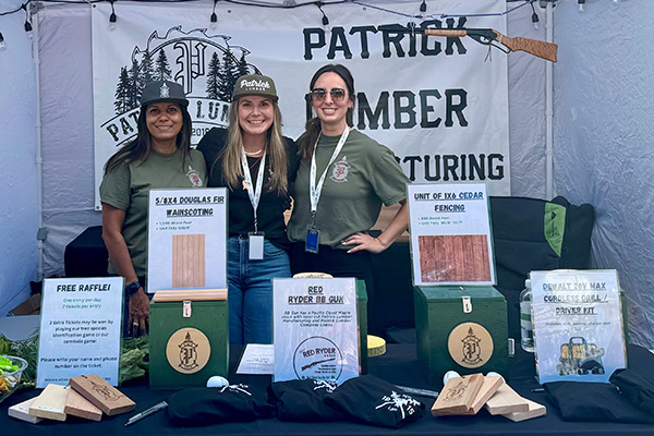 Three representatives of Patrick Lumber at a table and booth at the fairgrounds. Free Raffle sign Wood samples