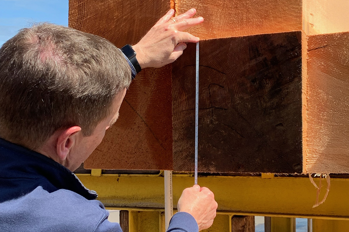 Picture of a lumber worker measuring a cut of wood