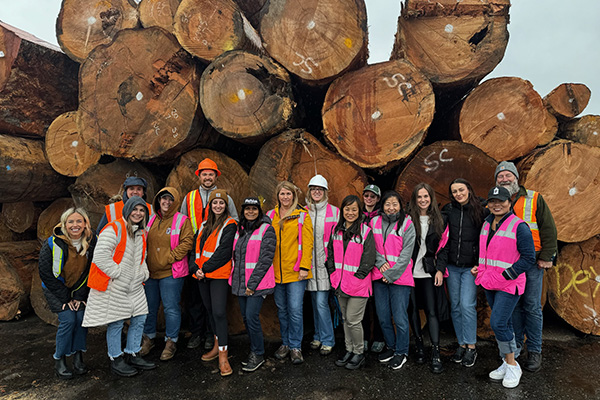 A group of people posing for a picture with lumber in the background